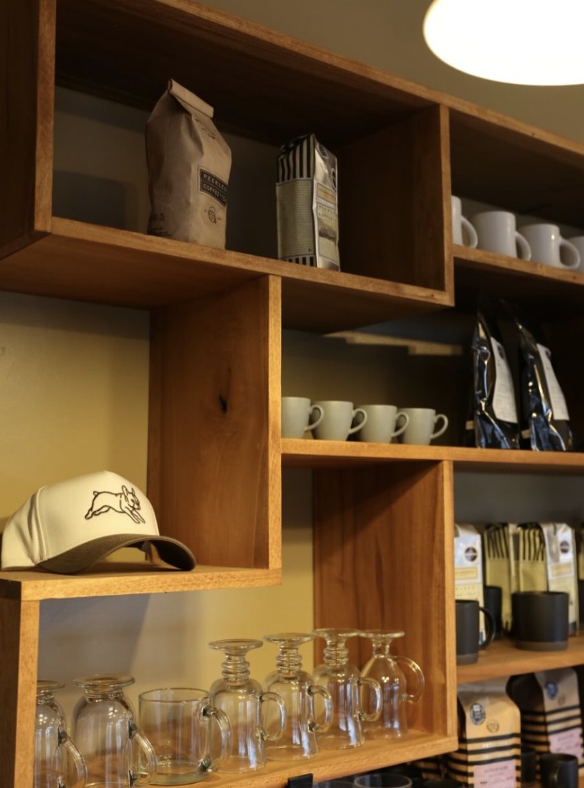 Retail shelves with coffee bags, mugs, and a Frenchies cap